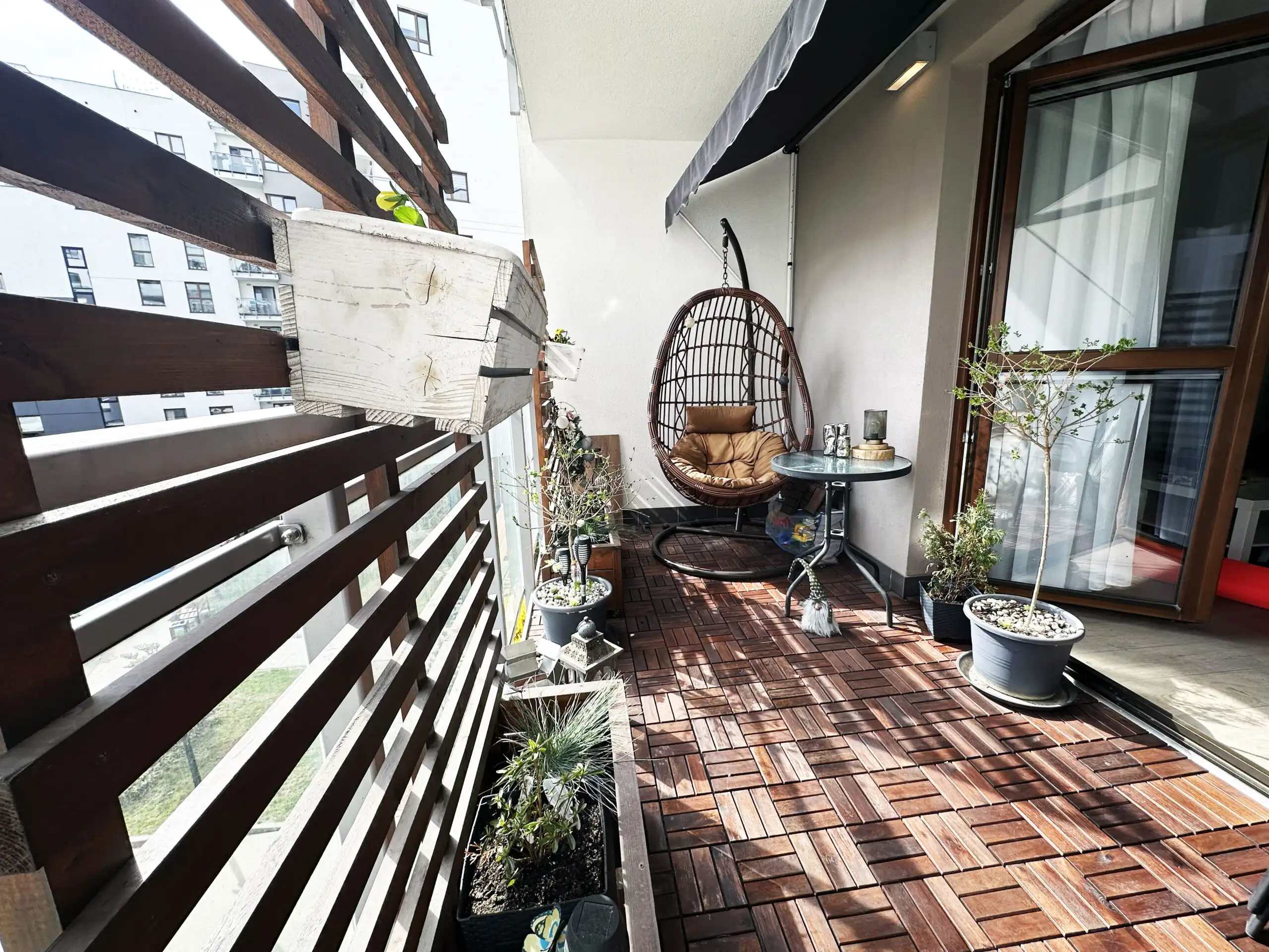 Balcony of a modern 2-bedroom apartment in Warsaw with outdoor seating and potted plants.