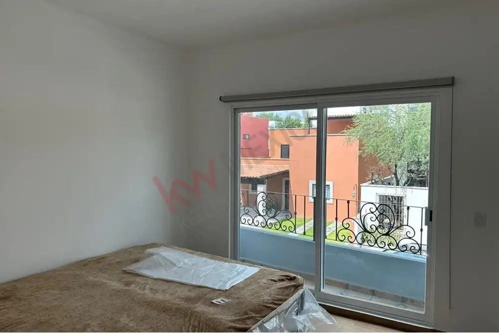 Bright bedroom with large sliding glass door and balcony view.