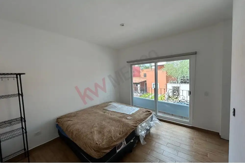 Bright bedroom featuring a large window and balcony access in a charming San Miguel de Allende home.
