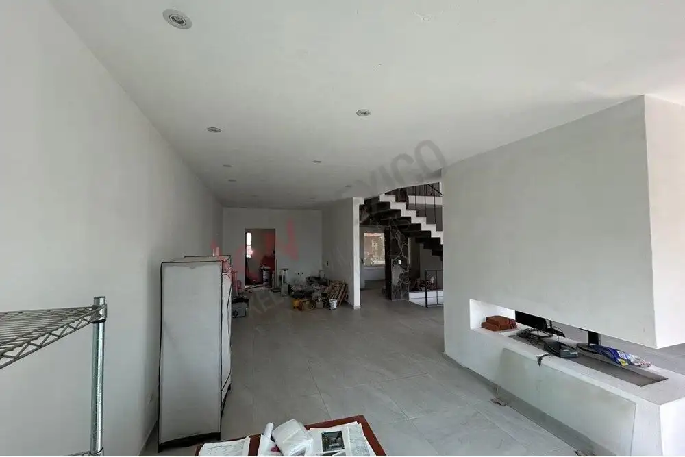 Spacious living area with white walls, staircase, and minimal furniture in a home for sale in El Cap.