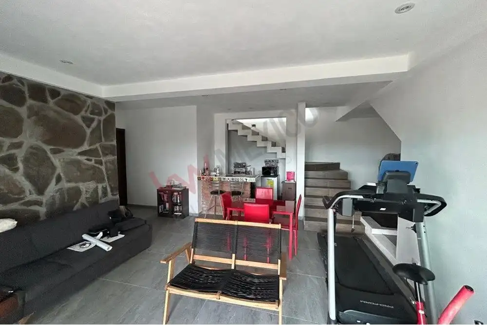 Spacious interior featuring a treadmill, sofa, and dining area with stairs leading to upper levels.