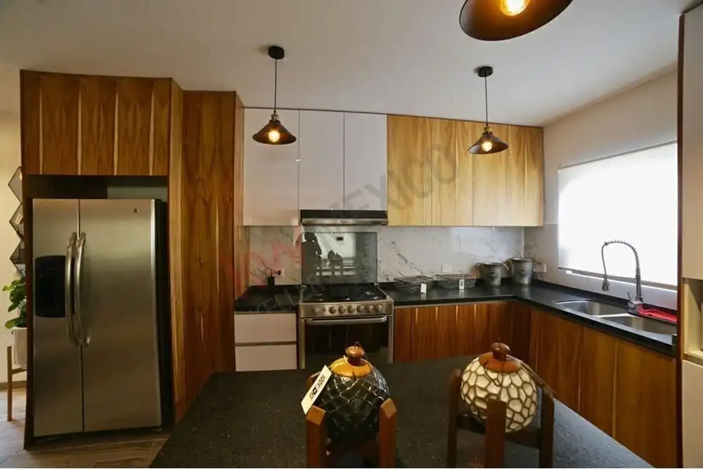 Modern kitchen with wooden cabinets, stainless steel fridge, and marble countertops.