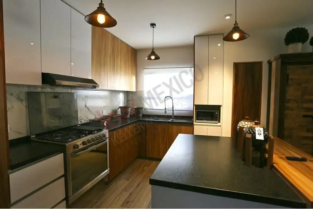 Spacious kitchen featuring wooden cabinets, black countertops, and modern appliances.
