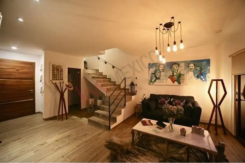 Bright living room with modern decor and artwork, featuring a staircase leading to the rooftop terra.