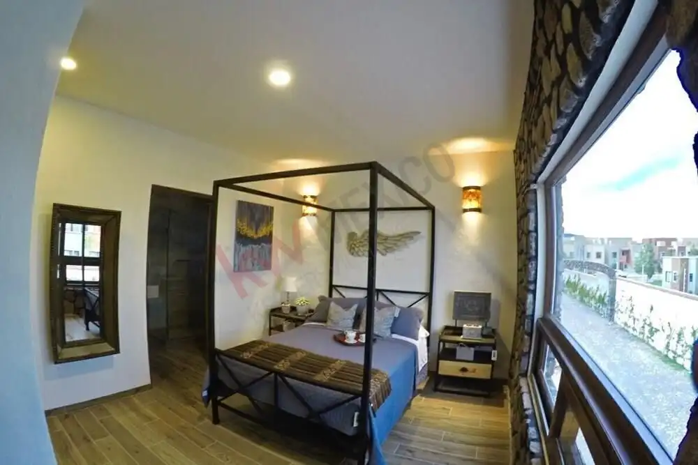 Spacious bedroom with modern decor, four-poster bed, and balcony overlooking city views.