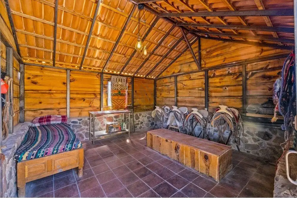 Stable interior with horses and wooden furnishings in a rustic ranch setting.