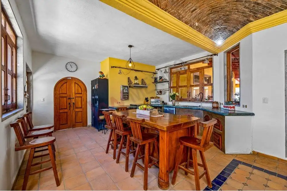 Cozy country kitchen with wooden dining table, open shelves, and rustic decor in a large estate.