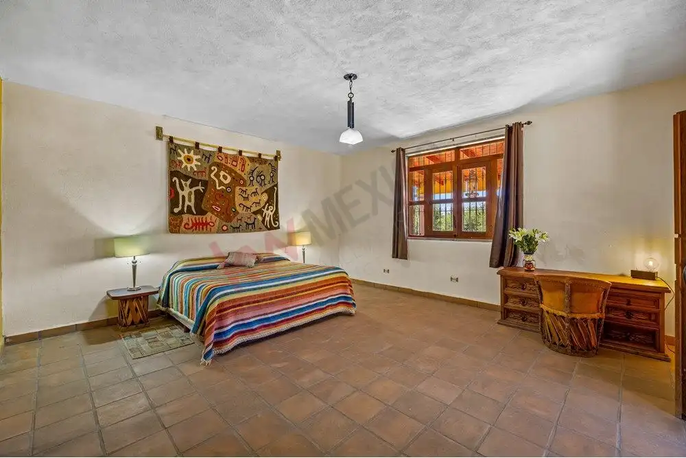 Spacious bedroom with colorful bedspread and large window in a country estate.