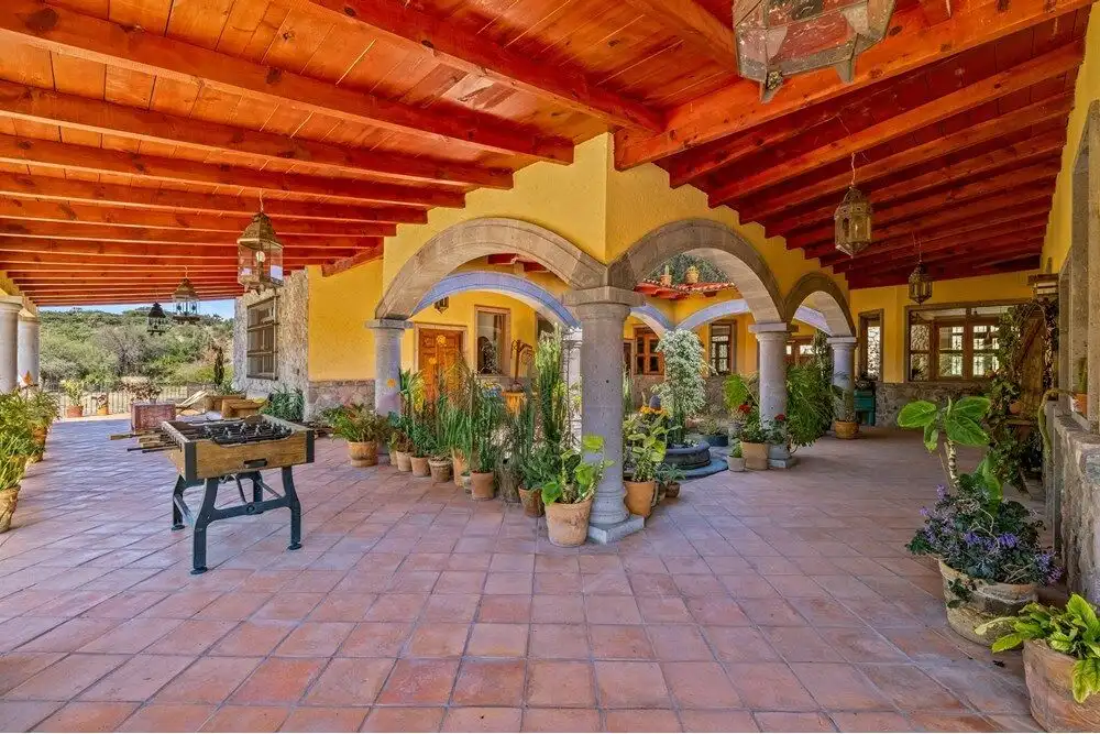 Spacious outdoor patio with arches, potted plants, and wooden ceiling in a large country estate in S.