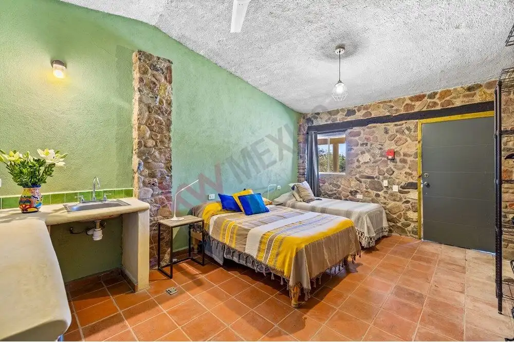 Comfortable guest bedroom with rustic stone walls and vibrant decor in a large San Miguel de Allende.