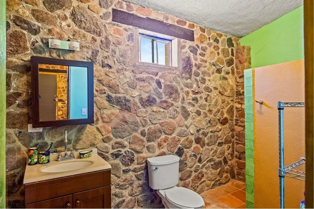 Stone bathroom with modern sink and toilet in a rustic country estate setting.