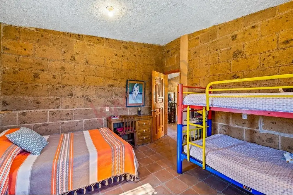 Comfortable bedroom with bunk beds and rustic brick walls in a large country estate.