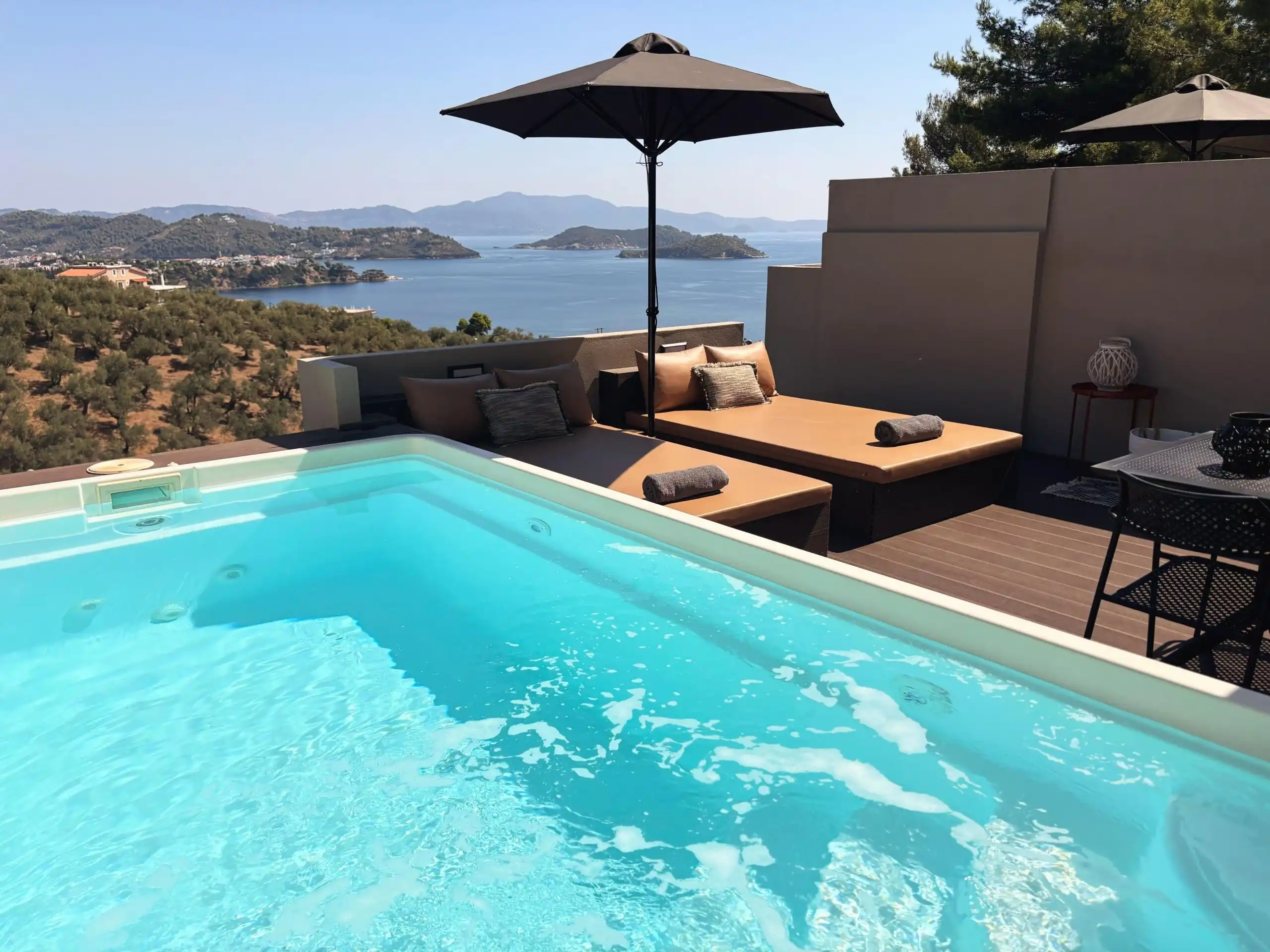 Stunning sea-view pool with sun loungers and umbrellas in a luxury villa complex in Skiathos, Greece.