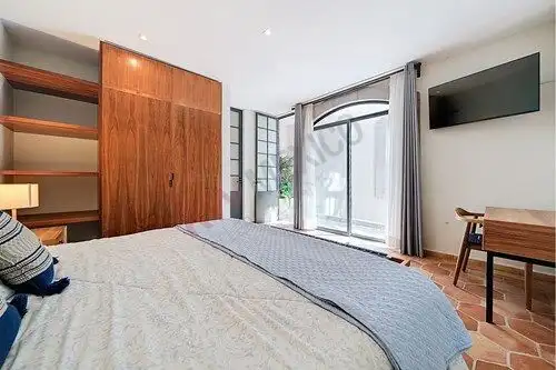 Spacious bedroom featuring large windows, wooden built-in shelves, and contemporary decor in San Mig.
