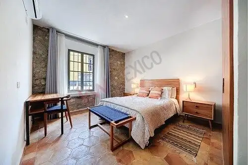 Comfortable bedroom with natural light, wooden furniture, and rustic accents in a charming home.
