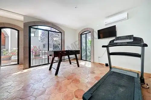 Bright living room with large windows and exercise equipment.