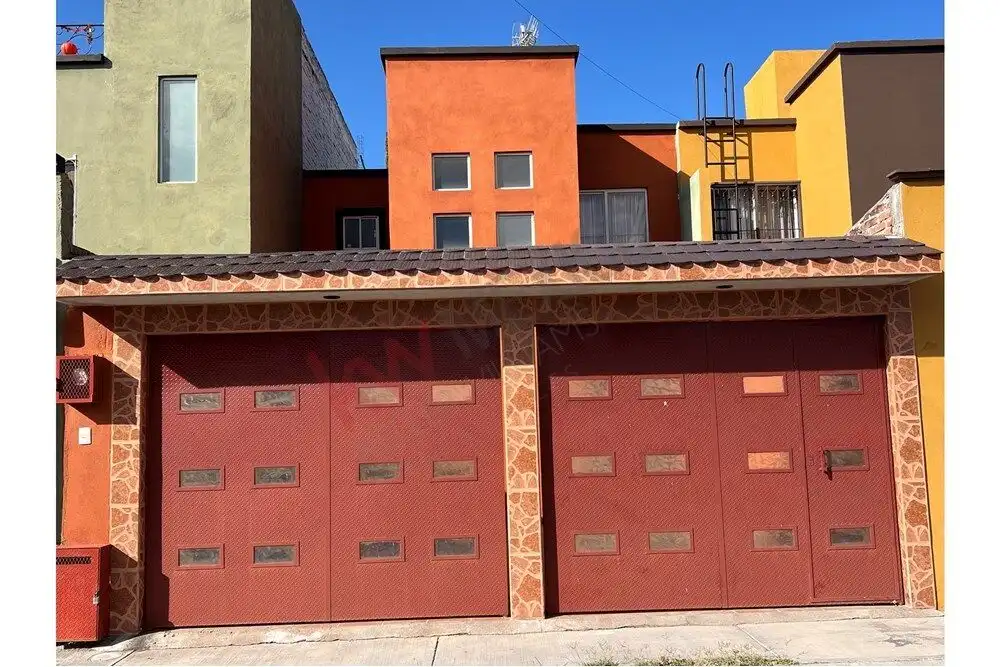 Colorful modern house with garage in San Miguel de Allende, Mexico. Bright red garage doors with small windows, surrounded by vibrant building facades.