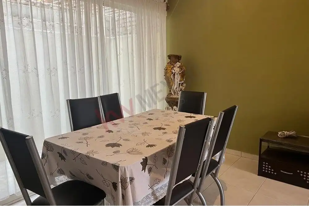 Cozy Dining Room in San Miguel de Allende Modern dining room with a table and six black chairs, bright natural light from large window.