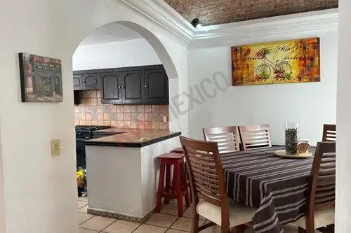 Cozy dining room with wooden table and chairs, adjacent to kitchen with black cabinets.