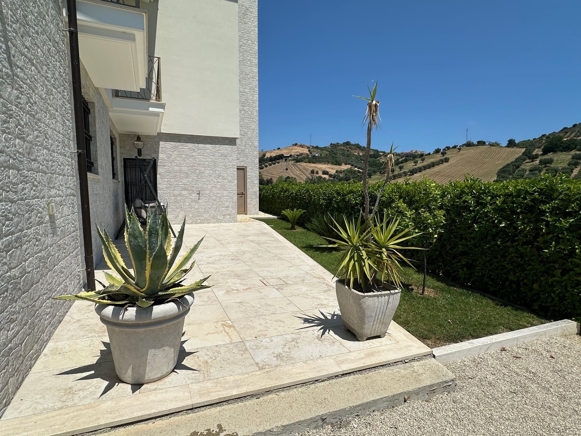 Luxury 5 Bed Villa for Sale in Tortoreto Elegant villa entrance with potted plants and scenic countryside view.