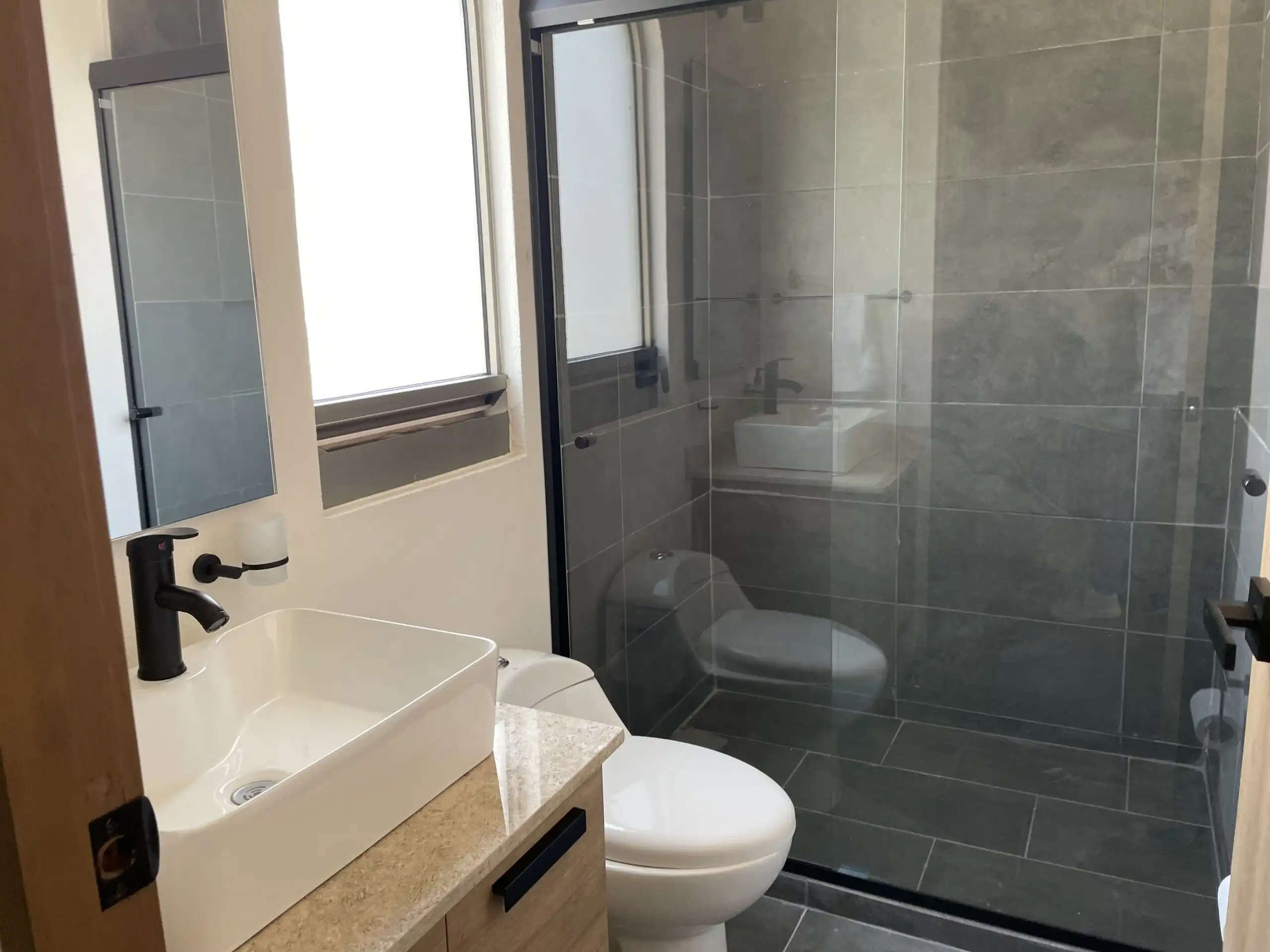 Bright bathroom with modern fixtures and glass shower in Residencial Barroco, San Miguel de Allende.