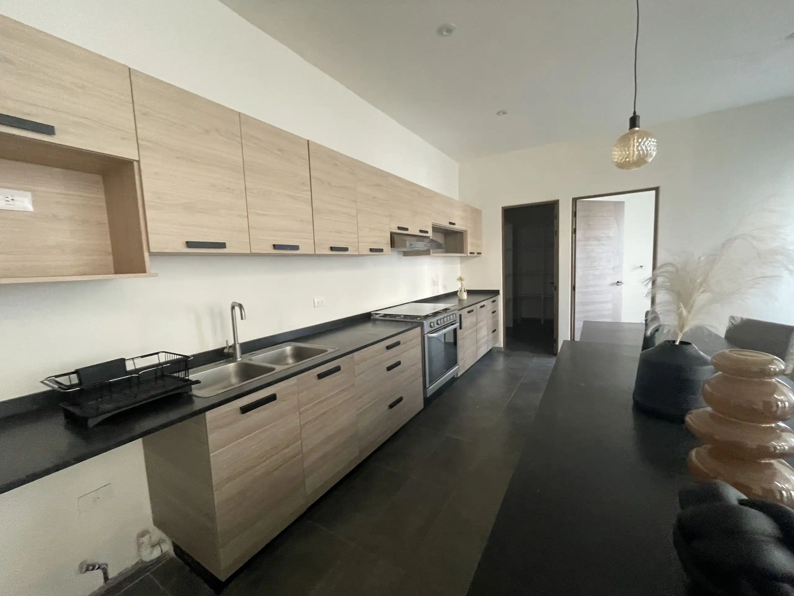 Modern Kitchen in Residencial Barroco Contemporary kitchen with wooden cabinets and black countertops in San Miguel de Allende.