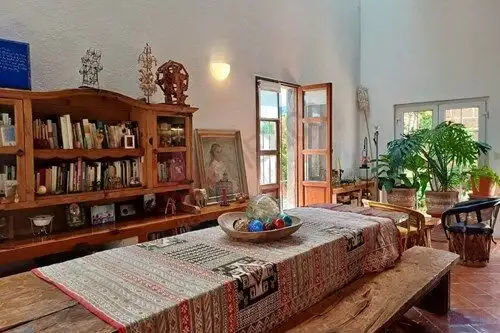 Cozy fully furnished loft with rustic decor, wooden furniture, and vibrant plants in a bright, airy.