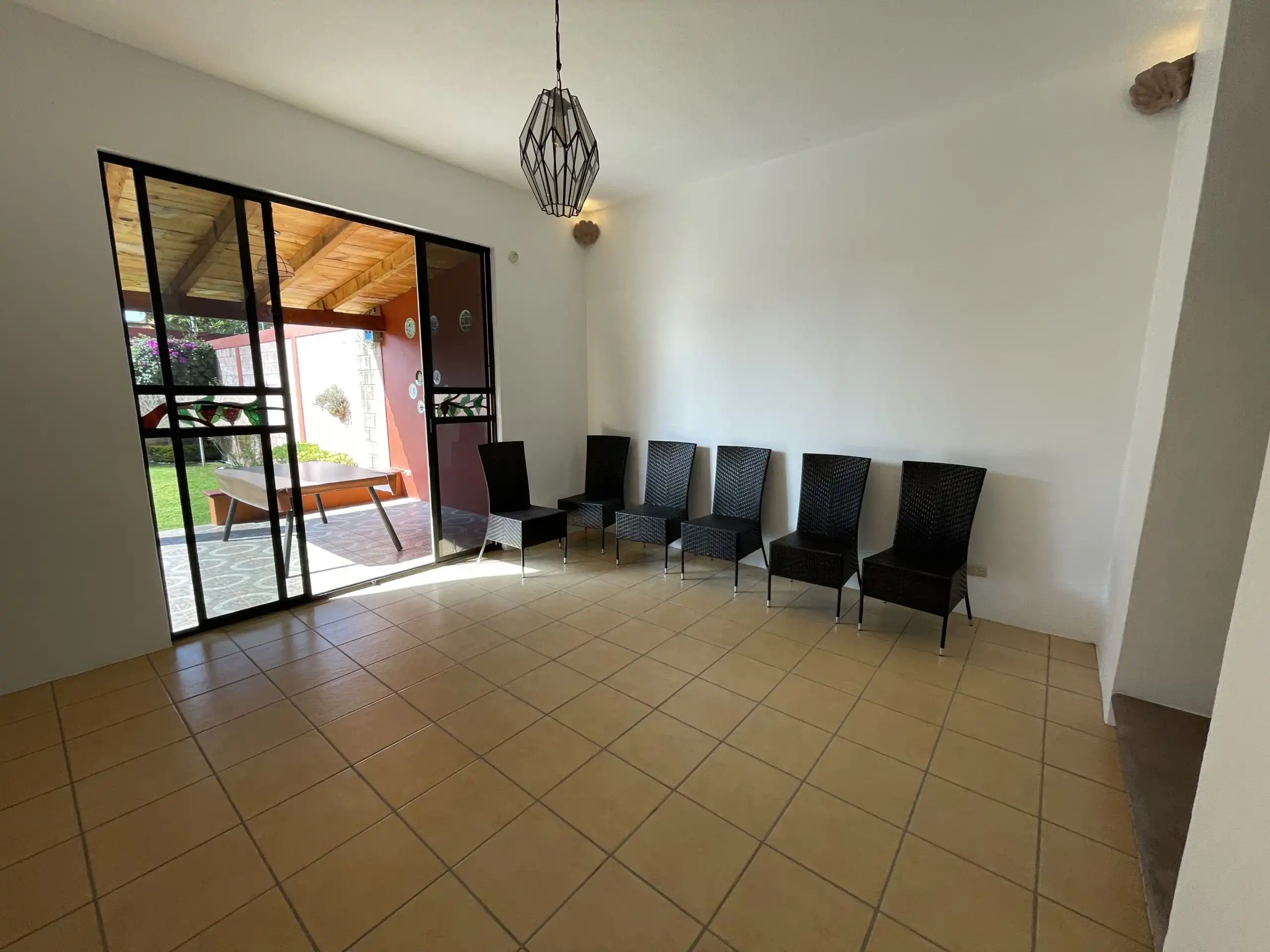 Bright living area with large glass doors opening to outdoor patio and garden. Modern decor with amp.
