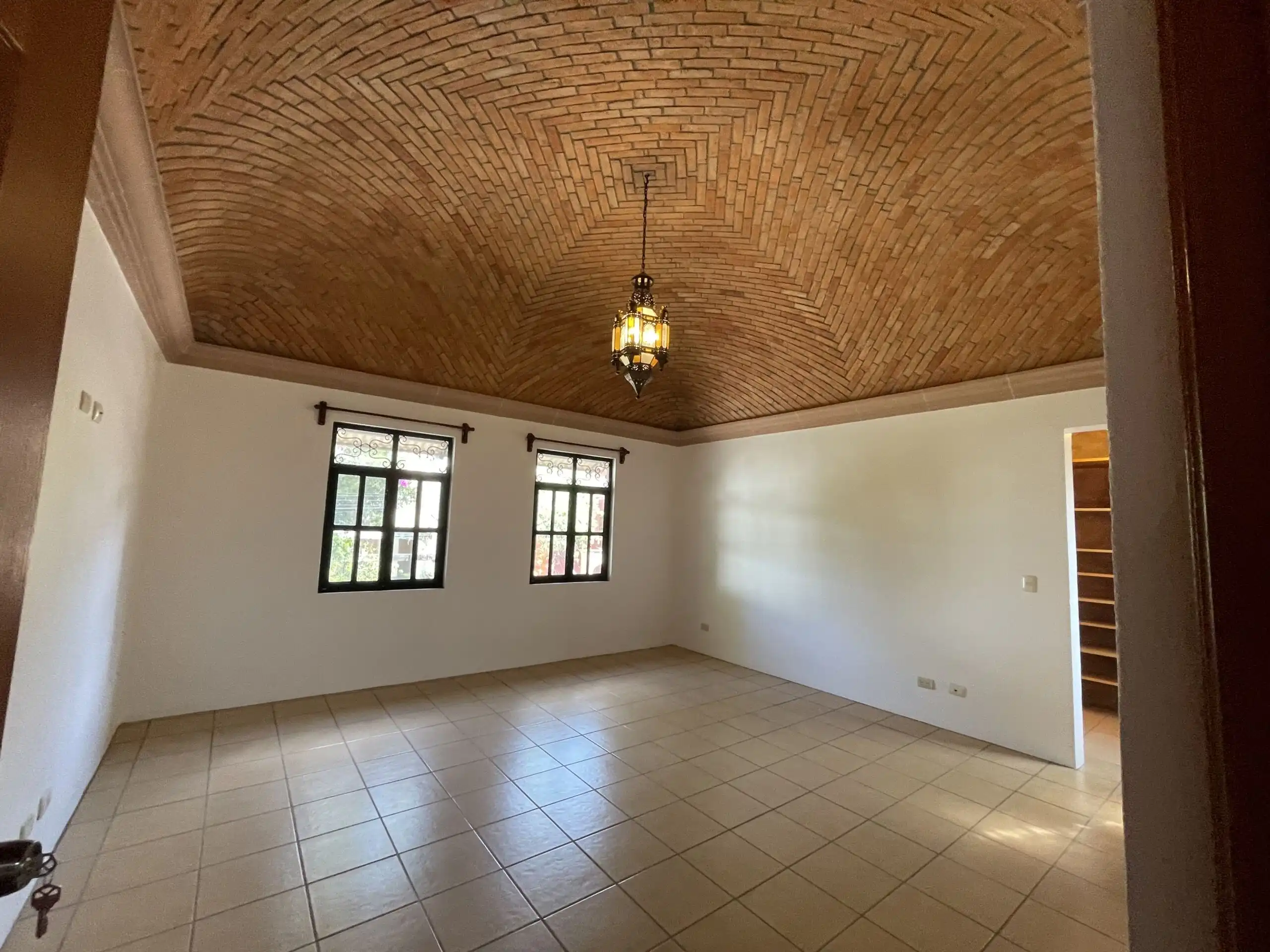 Spacious living area featuring a stunning brick vaulted ceiling and natural light from multiple wind.