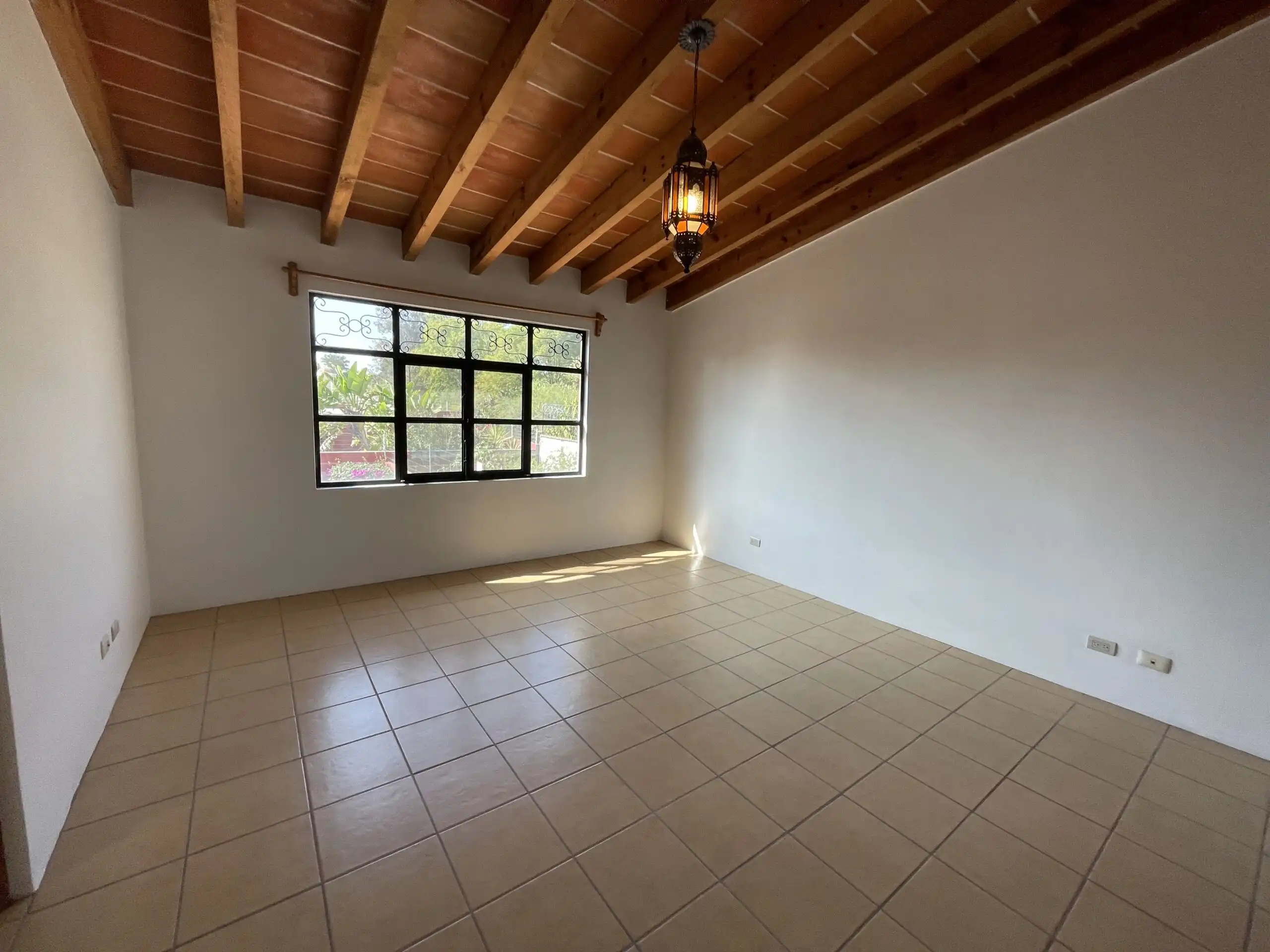 Spacious empty room with wooden ceiling, large window, and tiled floor in Los Frailes home.