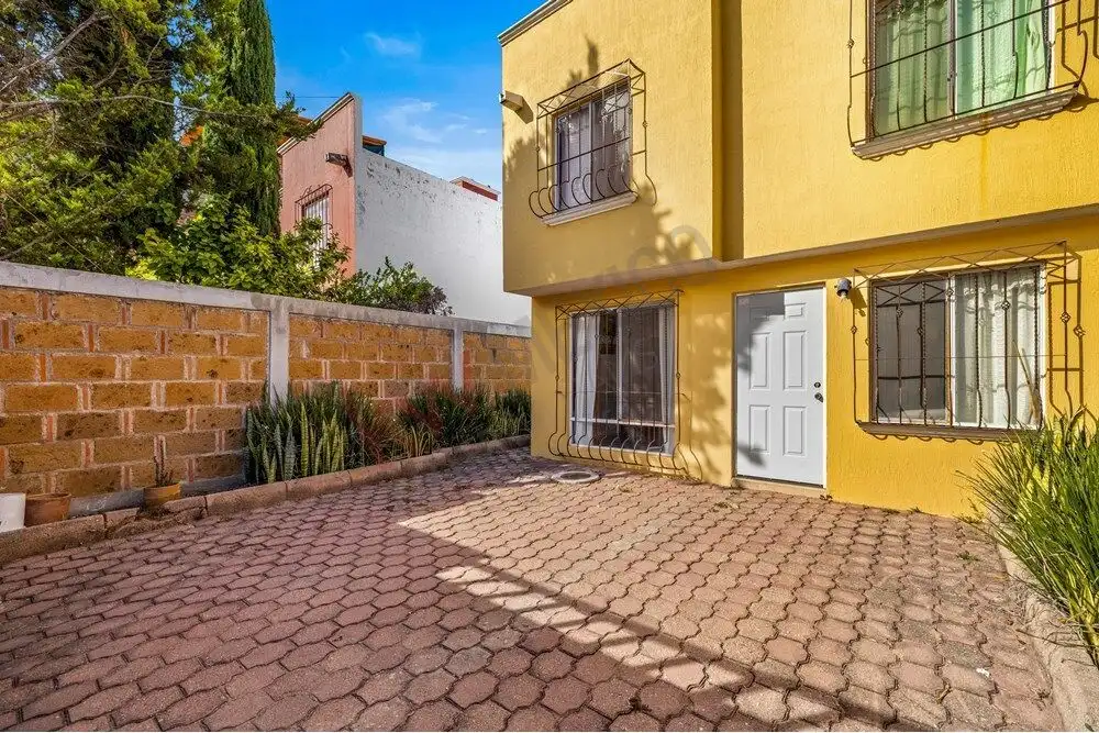 Bright yellow house with a paved courtyard and decorative window bars.