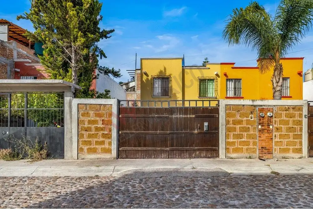 Colorful yellow house with a wooden gate and palm trees in San Miguel de Allende.