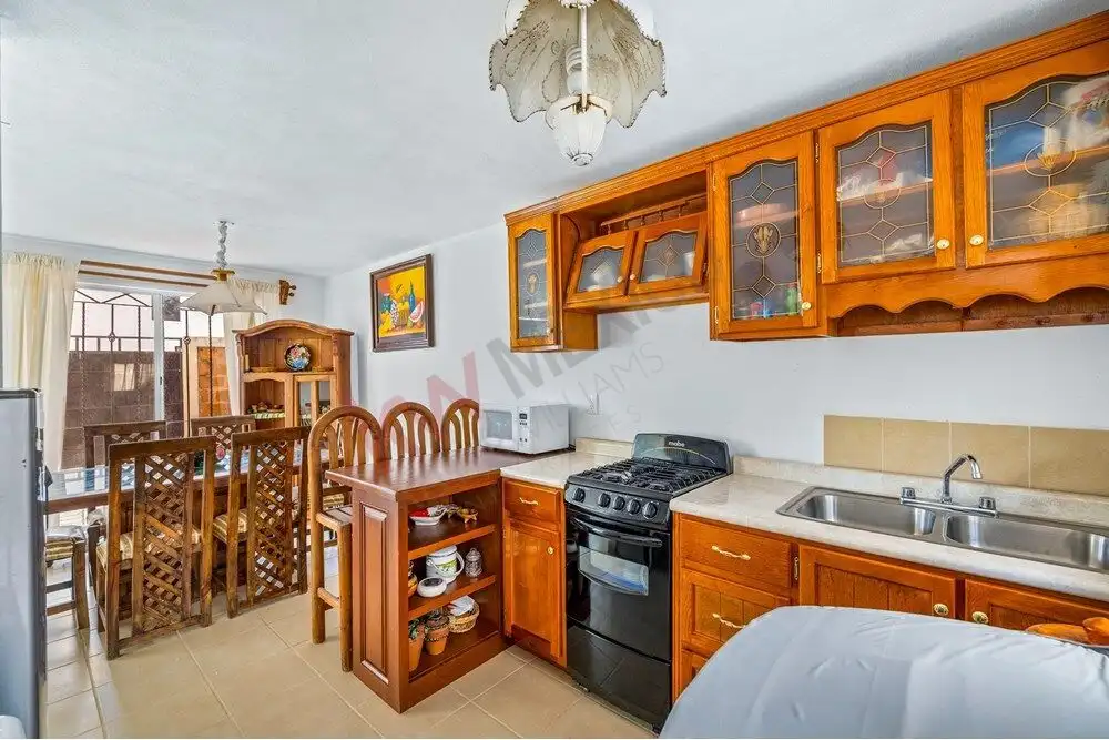 Charming kitchen with wooden cabinets, stove, and dining area in a cozy home close to Centro.