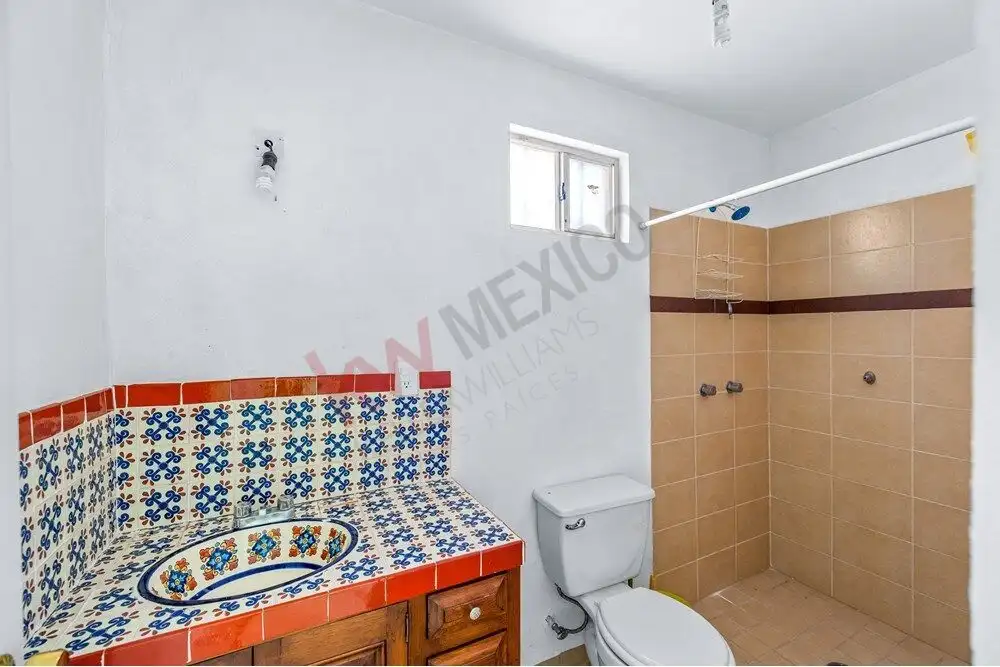 Charming bathroom with colorful tiled sink and modern toilet in a cozy home near Centro.