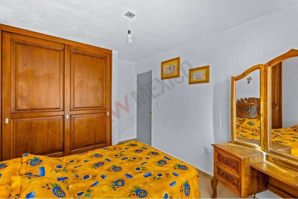 Comfortable bedroom featuring wooden wardrobe and dresser in a bright, inviting space.