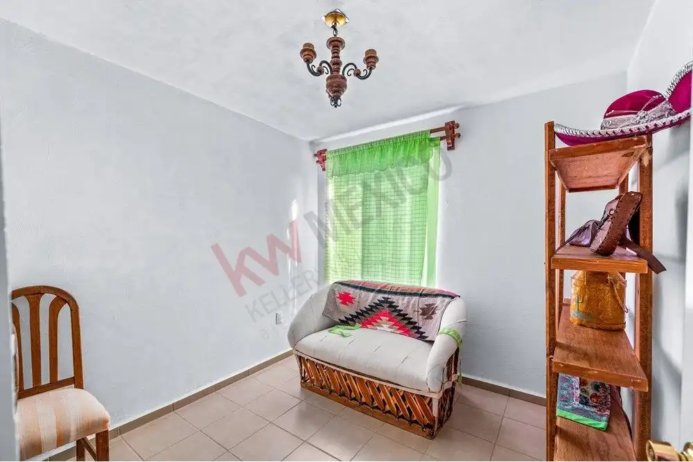 Charming living space with a sofa, green curtains, and wooden shelves in a home near Centro.