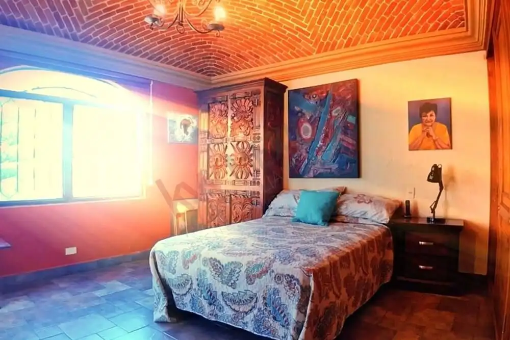 Bright bedroom featuring colorful artwork and a large window with natural light.
