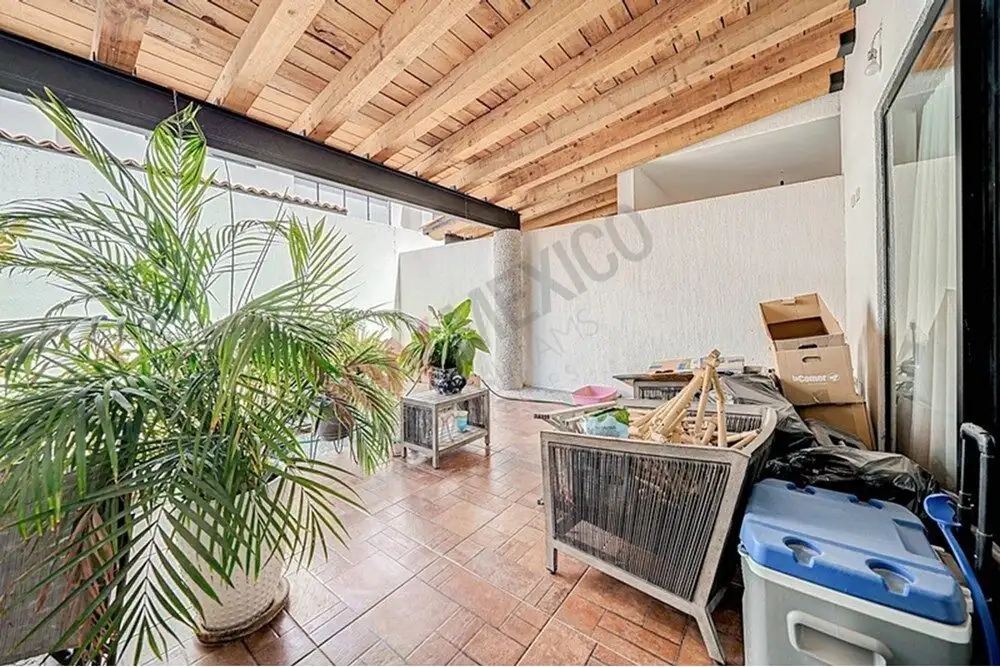 Balcony with potted plants and outdoor furniture in a spacious, covered terrace.