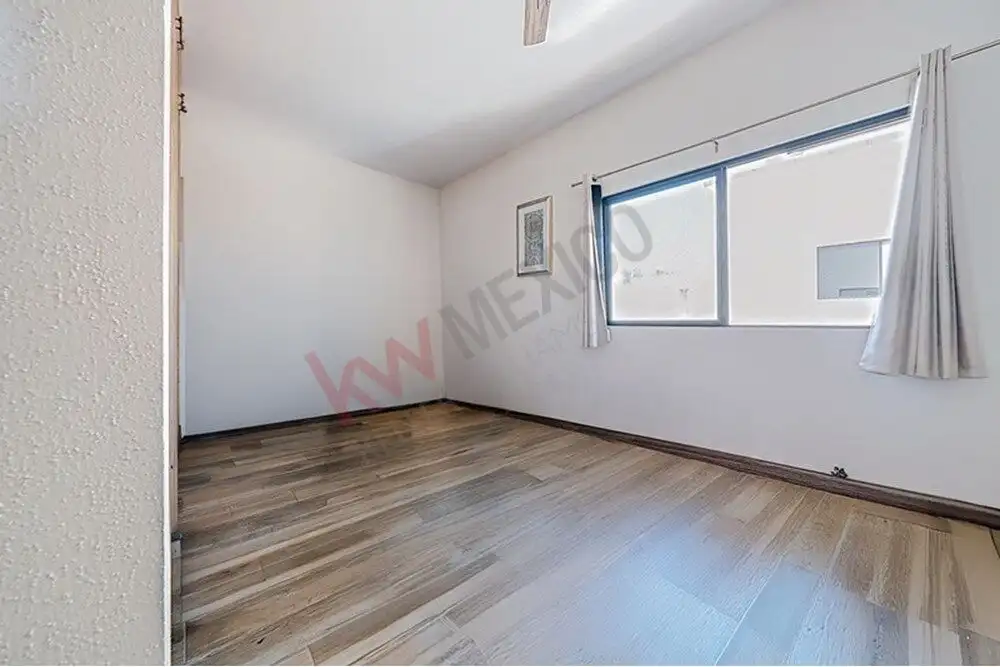 Bright, spacious room with large window and wooden flooring in a modern home.