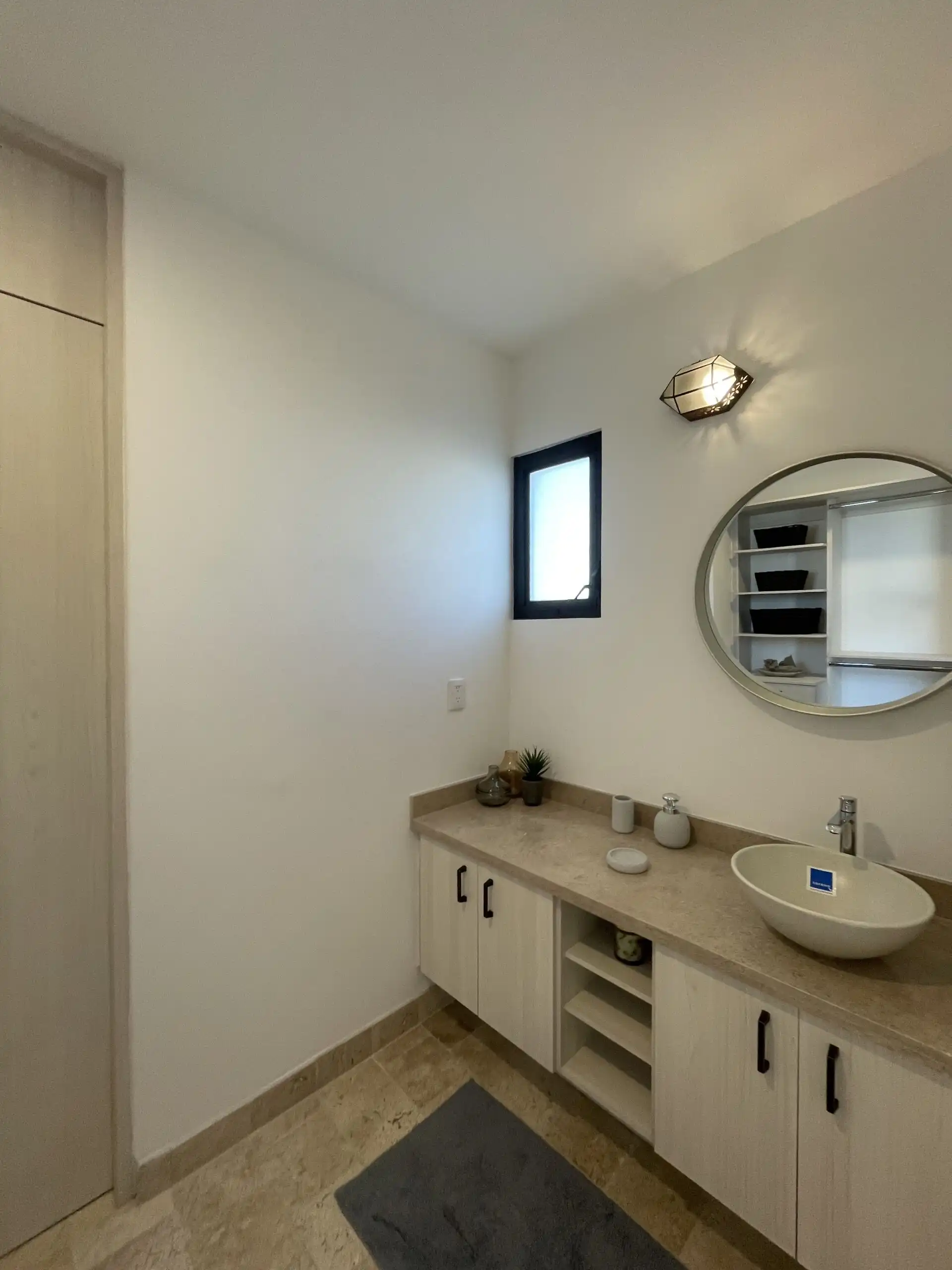 Bright bathroom featuring a sleek vanity with a round mirror and modern accessories.