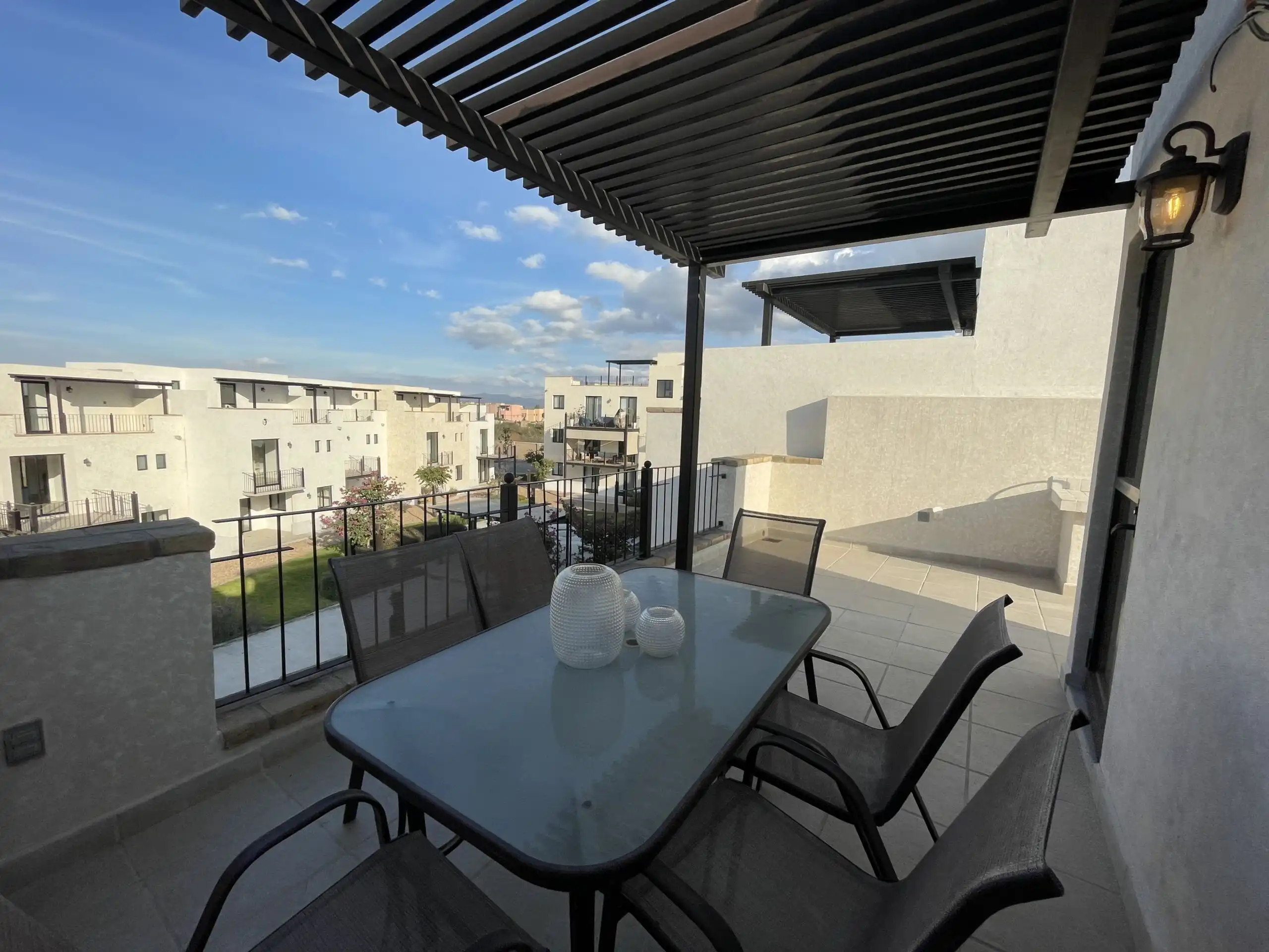 Balcony with outdoor dining table, chairs, and cityscape view in Casa Santa Elena, La Luminaria.