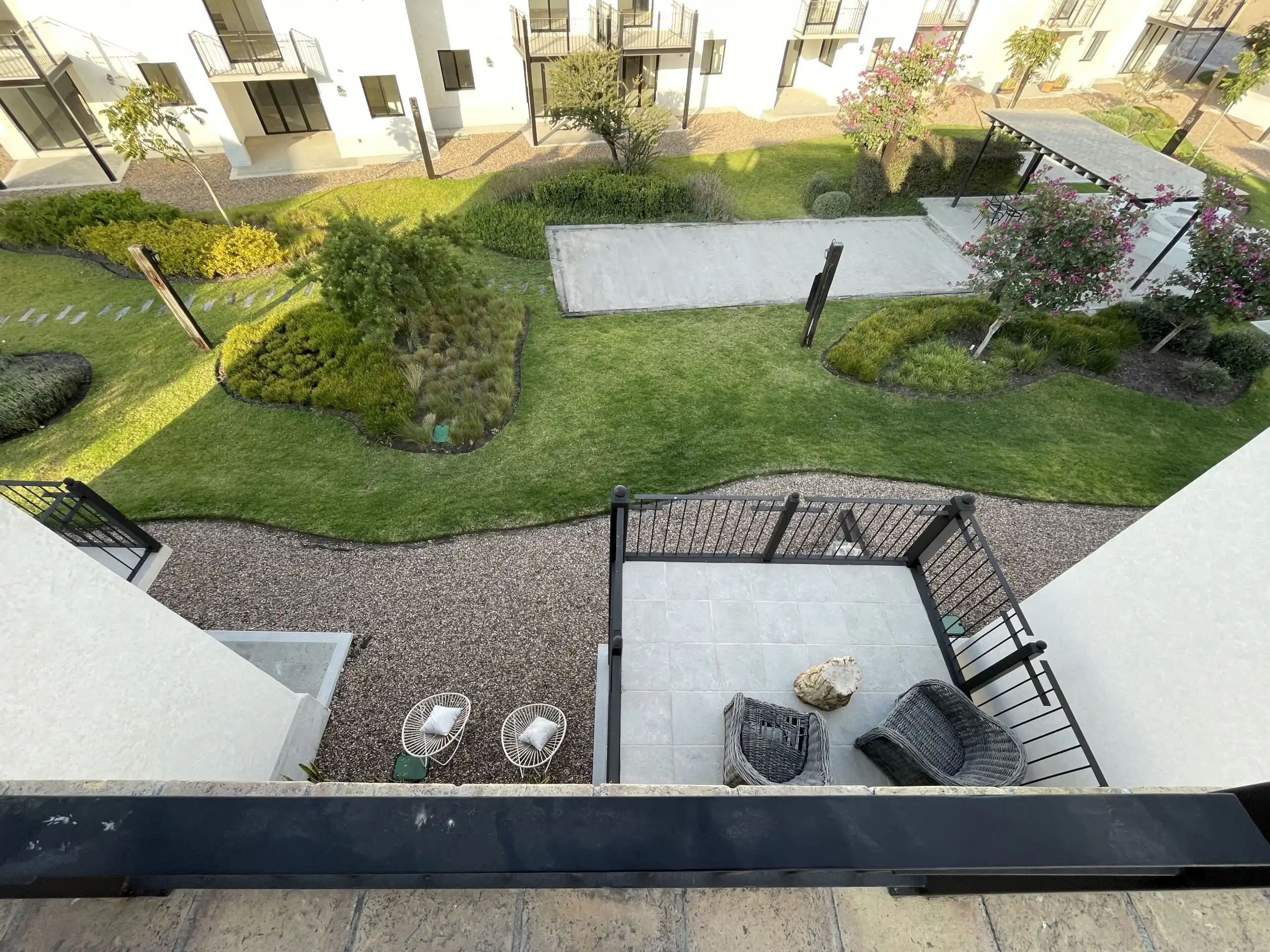 View of modern home garden with lush greenery, patio, and heated pool in San Miguel de Allende.
