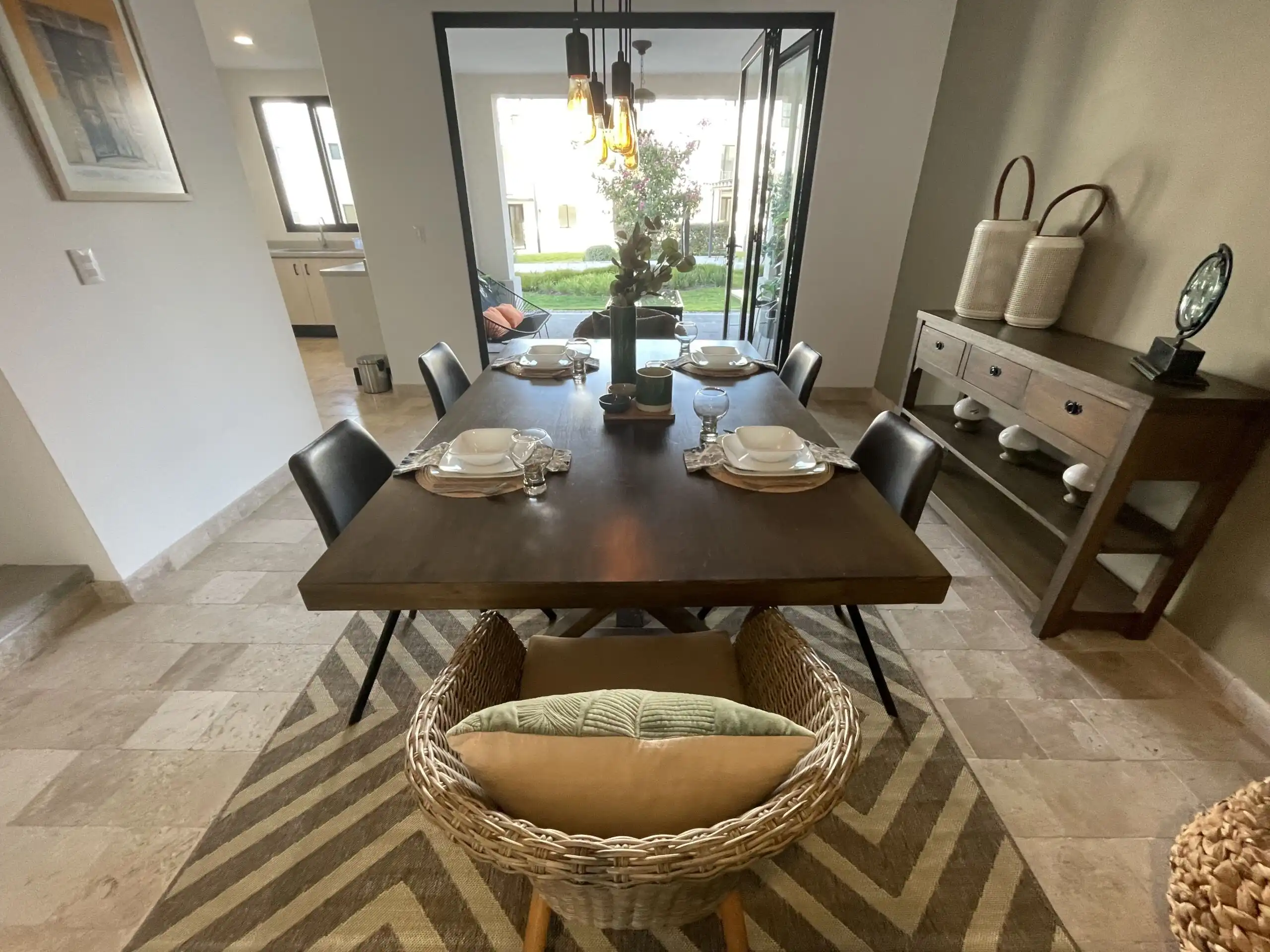 Luxury Dining Room with Modern Decor and Natural Light Elegant dining area featuring a wooden table, stylish chairs, and large glass doors opening to outdo.