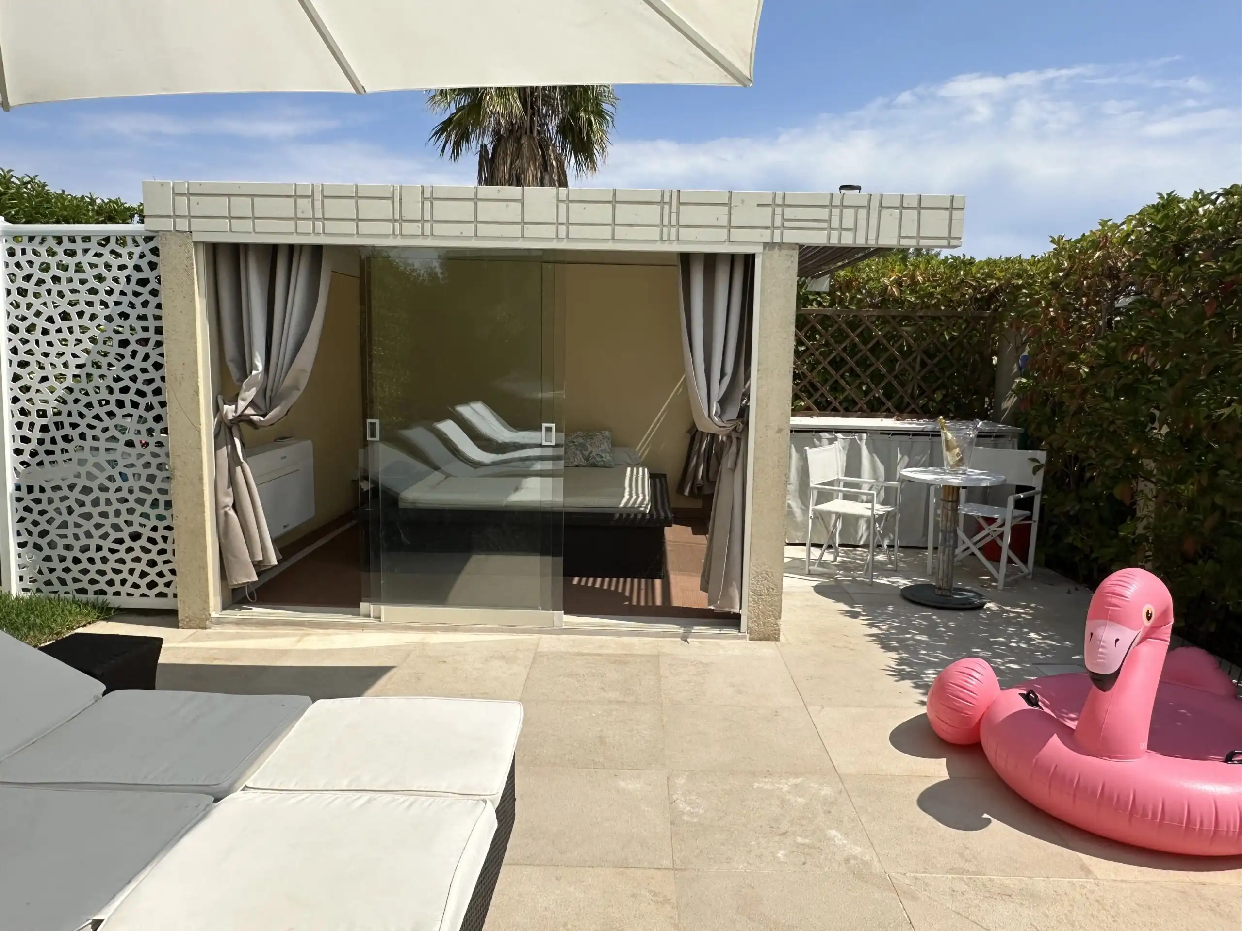 Elegant outdoor pool area with sun loungers and pink flamingo float.