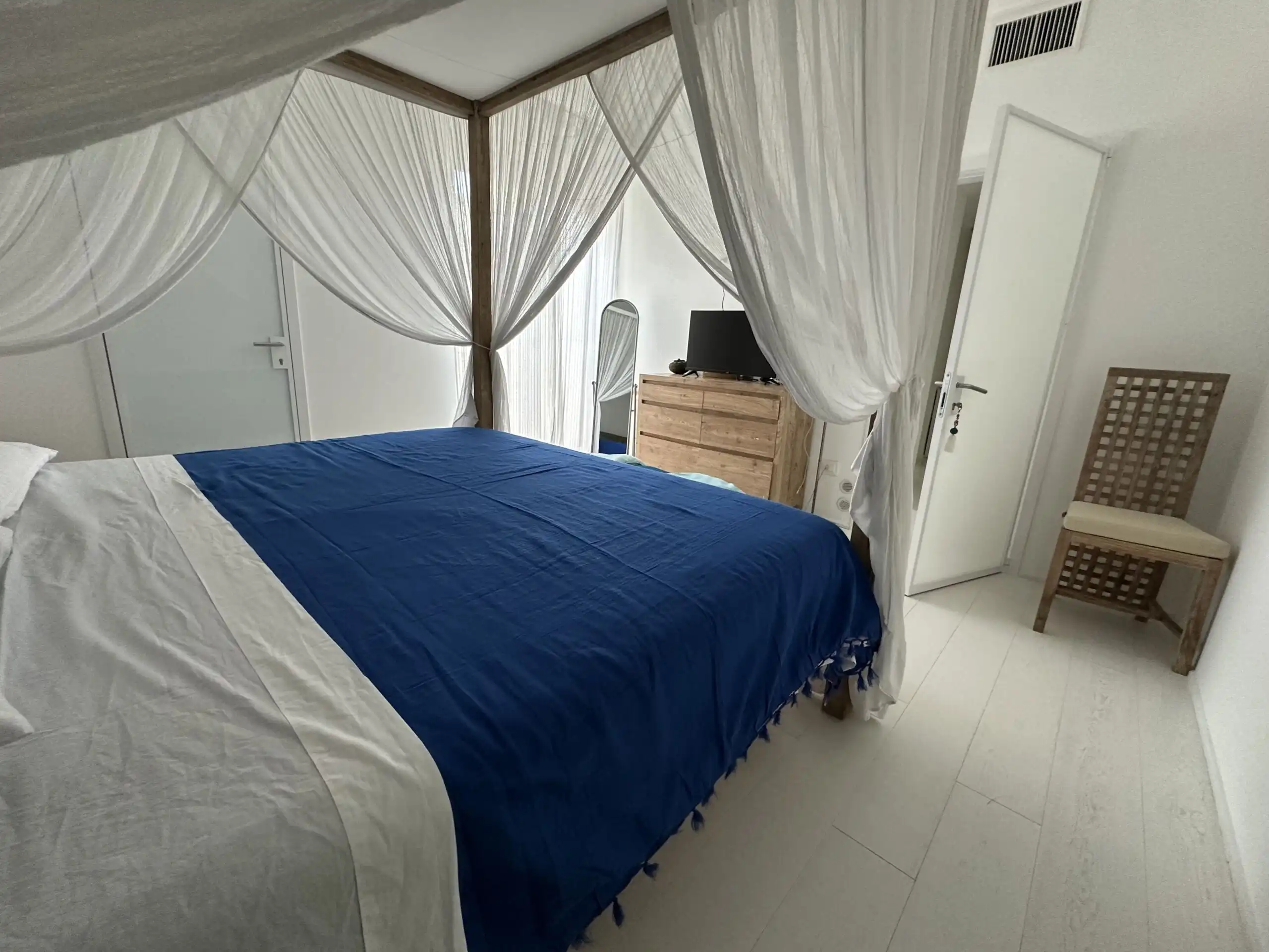 Elegant bedroom with a white canopy bed and blue bedding, offering a luxurious and relaxing atmosphe.