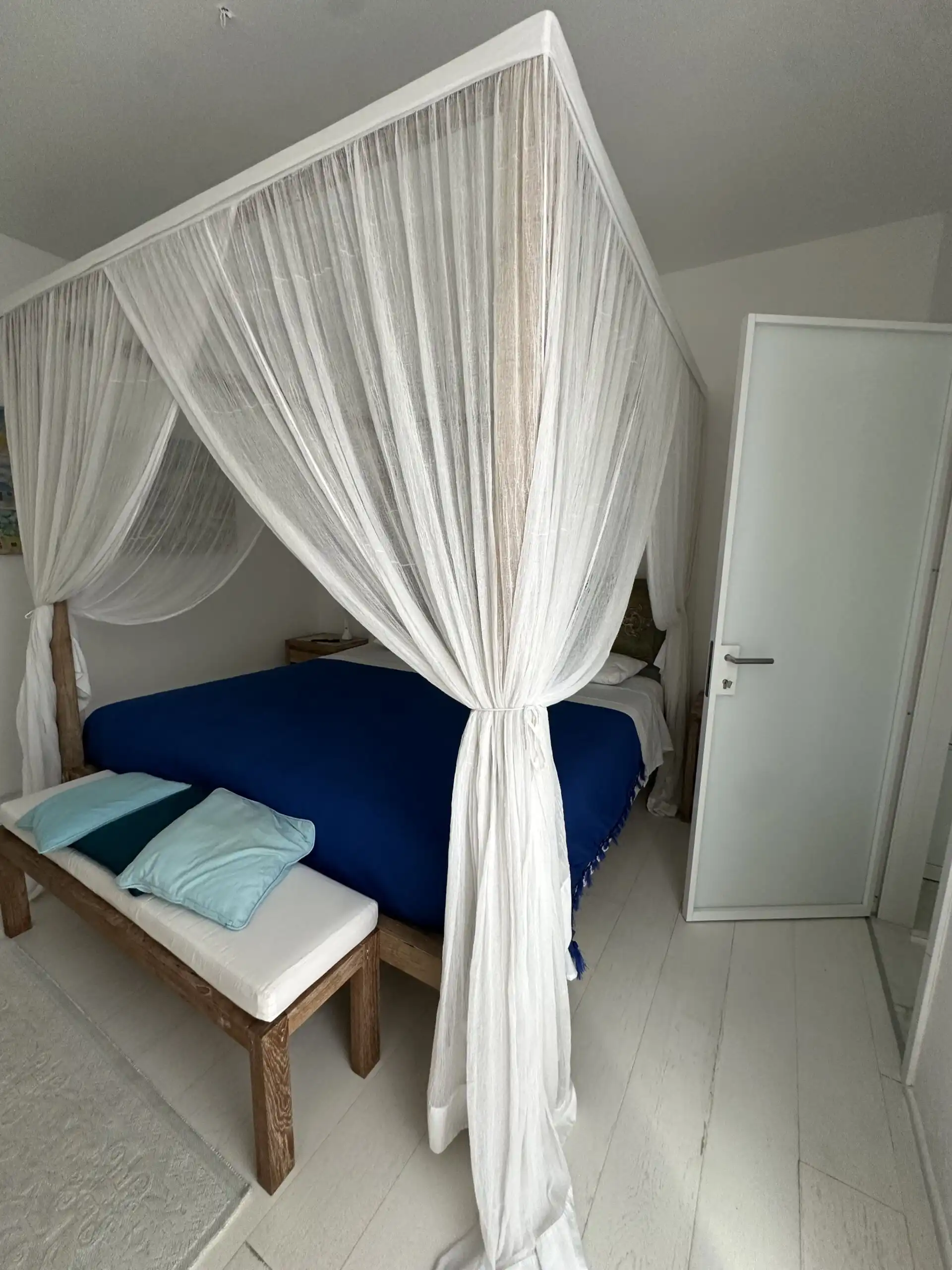 Elegant bedroom with a white canopy bed and sea views in Otranto, Puglia.