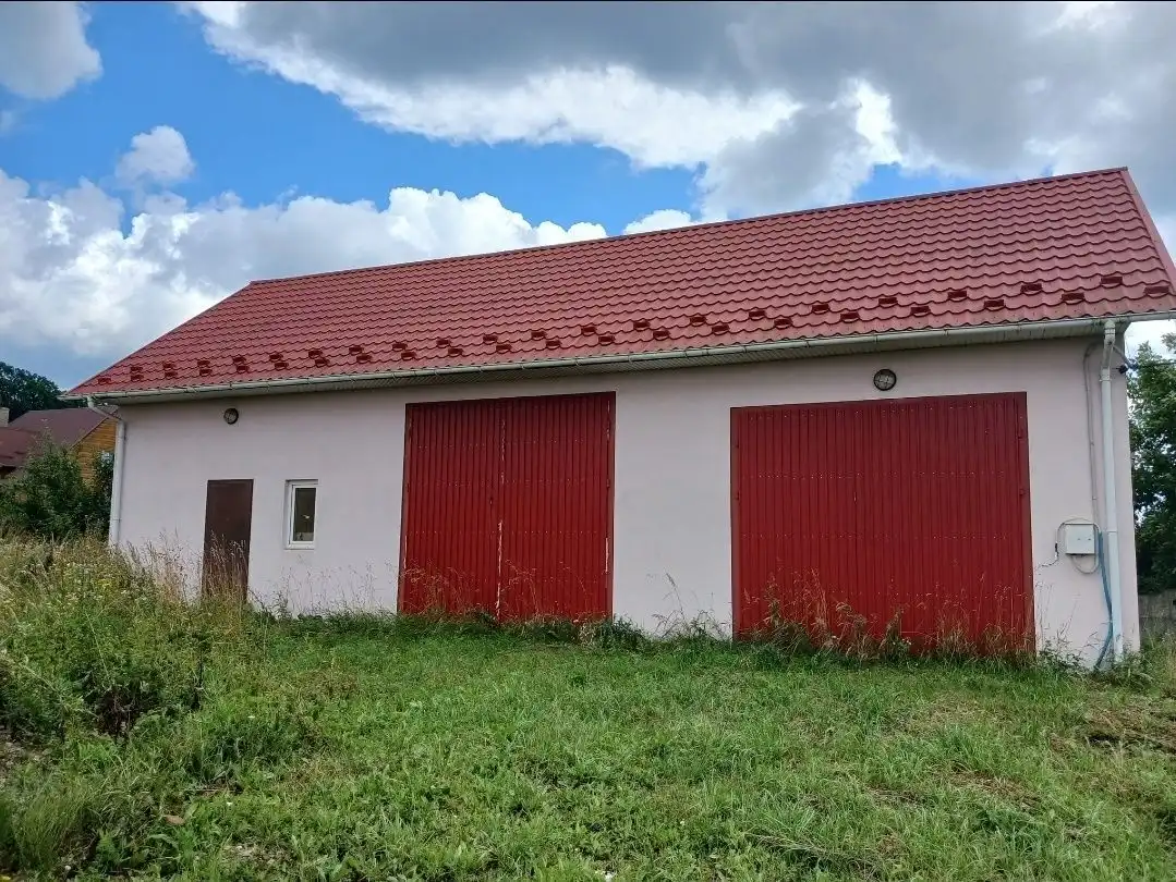 Bright duplex house with red doors and roof in a lush green setting.