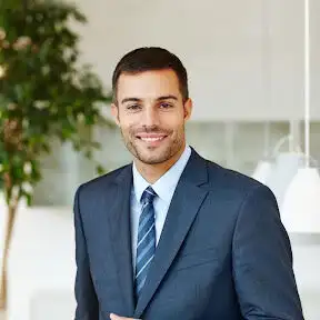 Business professional in a suit smiling in an office setting.