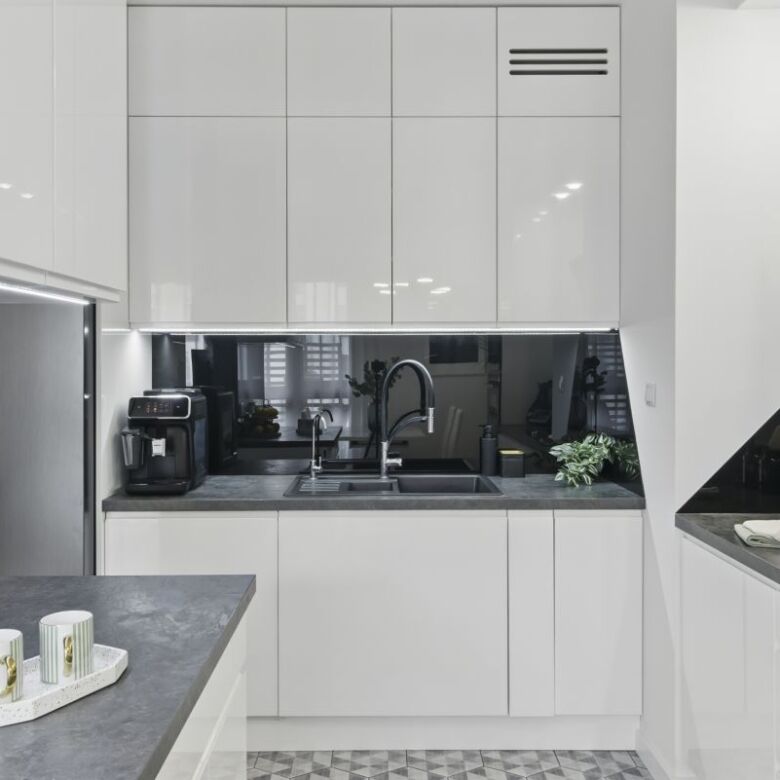 Modern 2-bedroom apartment kitchen in Warsaw with sleek white cabinets and contemporary appliances.