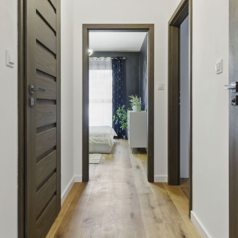 Bright hallway in Warsaw apartment with wooden doors and natural light from bedroom.